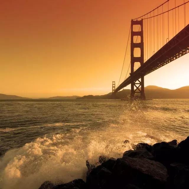 Les vagues s'écrasent près de Fort Point, sous le Golden Gate Bridge, au coucher du soleil.