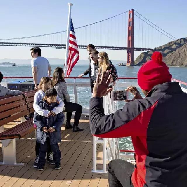 A family enjoys a cruise on the bay, passing the Golden Gate Bridge.