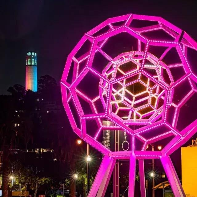 Buckyball shines outside the Exploratorium, with Coit Tower in the background